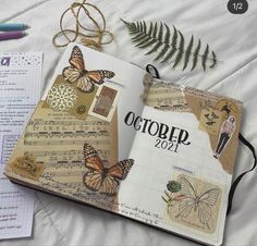 an open book with butterflies on it next to some paper and scissors, along with other items