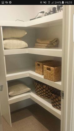 a closet with shelves and baskets on the bottom shelf, filled with linens and other items