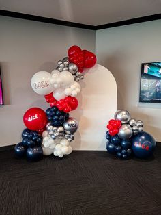 the balloon arch is decorated with red, white and blue balloons in an office setting