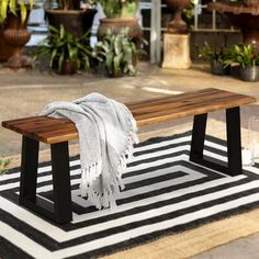 a wooden bench sitting on top of a black and white rug