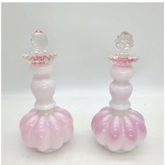 two pink and white glass candlesticks sitting next to each other