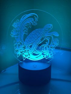 an illuminated turtle is sitting on top of a flowery base with blue light in the background