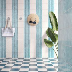 a blue and white tiled bathroom with a hat hanging on the wall next to a potted plant