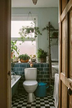 an open door leading to a bathroom with plants on the wall and tiled flooring