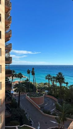 the view from an apartment balcony looking out at the ocean and palm trees in front of it