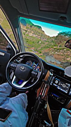 a man driving a vehicle down a road next to a lush green hillside