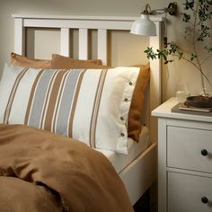 a bed with two pillows on top of it next to a night stand and lamp