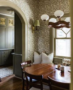 a dining room table and chairs in front of a window with an archway leading into the kitchen