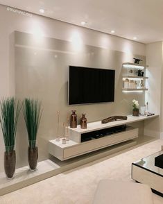 a living room with white furniture and a flat screen tv mounted on the wall above it