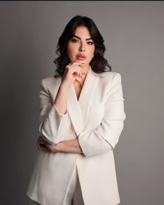 a woman in a white suit posing for a photo with her hands on her chin