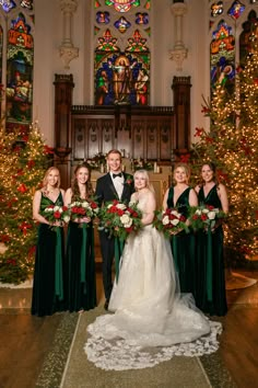 a bride and groom posing with their bridals in front of christmas trees at the cathedral