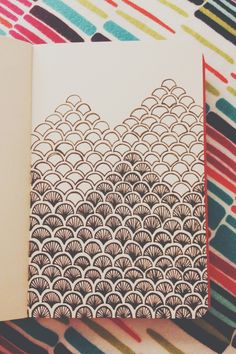 an open book on top of a colorful table cloth with lines and circles in the background