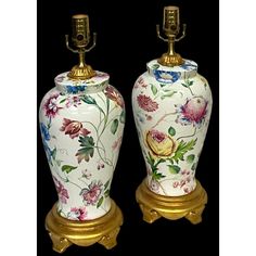 two white and gold vases with flowers painted on them, one is turned to the side