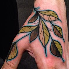 a person's hand with a leaf tattoo on it