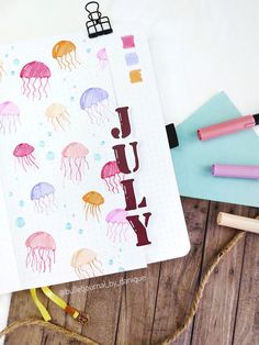 an open notebook with watercolor jelly on it and some pencils next to it