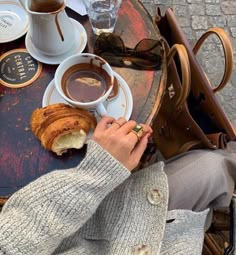 a person sitting at a table with coffee and croissants