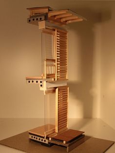 a model of a building made out of wooden slats and wood planks on top of a piece of cardboard