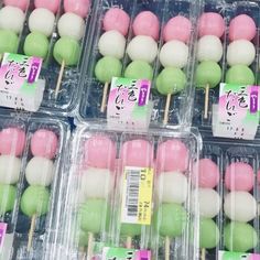 several plastic containers filled with green and pink lollipops on toothpicks