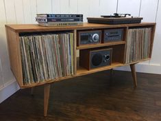 an old record player sitting on top of a wooden shelf with records and vinyls