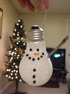 a snowman ornament hanging from the ceiling in front of a christmas tree