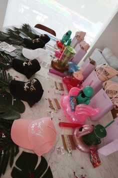 many hats are lined up on the table with palm leaves and other items around them