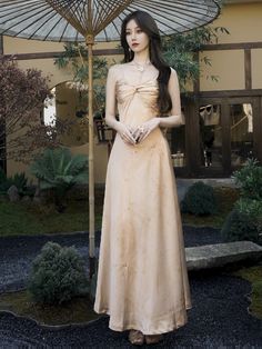 a woman in a long dress standing under an umbrella