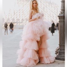 a woman in a pink dress leaning against a pole