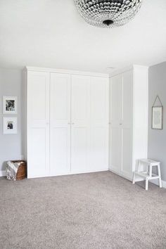 an empty room with white closets and gray carpeted flooring is pictured in this image