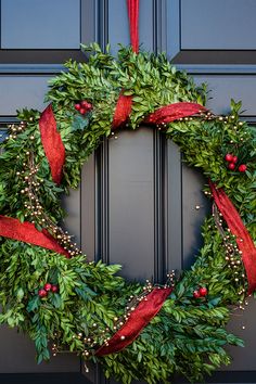 a green wreath with red ribbon hanging on the front door to give it a festive touch