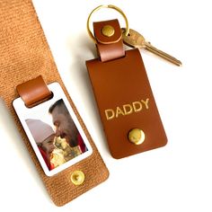 a keychain with a photo attached to it next to a leather tag that says daddy