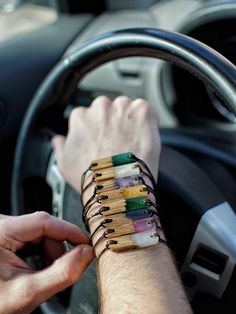 a man is holding the steering wheel of a car with matches in his bracelets