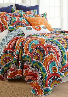 a bed with colorful comforters and pillows