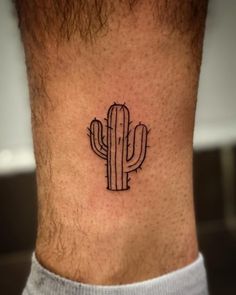 a small cactus tattoo on the side of a man's leg, with black ink