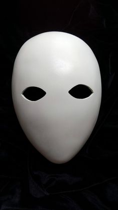 a white mask with black eyes on a black background