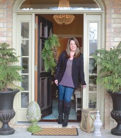 a woman standing in the doorway of a house with potted plants on either side