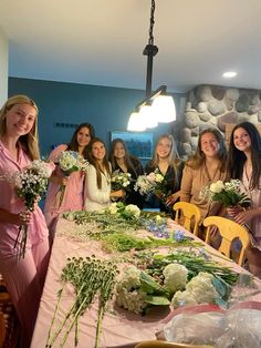 a group of women standing around a table with flowers