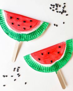 two paper plates with slices of watermelon on them and seeds scattered around it