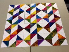 the quilts are all different colors and patterns on the table top, but they have been cut into squares