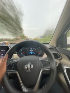 a person driving a car on the road with their hands on the steering wheel and dashboard