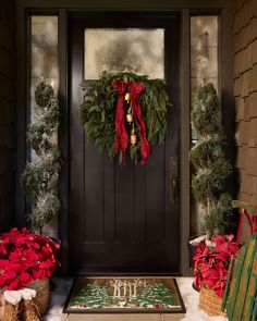 a front door decorated for christmas with poinsettis and wreath