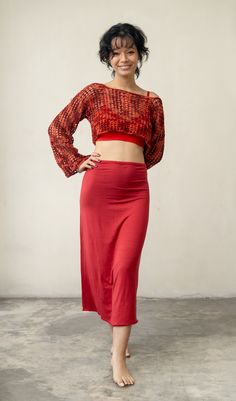 a woman standing in front of a white wall wearing a red skirt and crop top