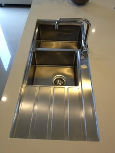 a stainless steel kitchen sink on a white countertop