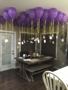 purple balloons are hanging from the ceiling above a dining room table