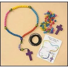 a rosary, bracelet, and cross on a table with a note attached to it