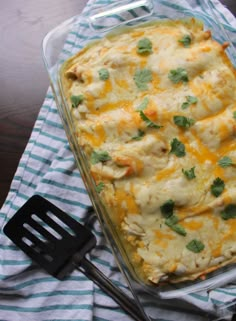 a casserole dish with chicken, cheese and cilantro on a table