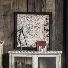 an old bookcase with some books on top of it and a framed painting in the background