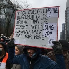 a man holding up a sign that says if you really think the environment is less important than the economy