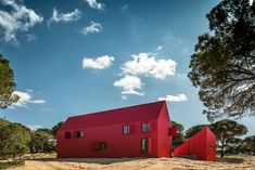 a red house sits in the middle of a dirt field