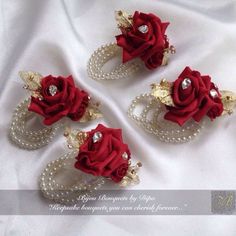 three red roses and pearls on white fabric