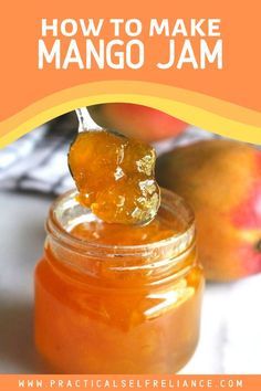 a jar filled with mango jam on top of a table next to two peaches